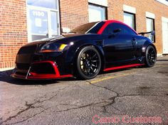 a black sports car parked in front of a brick building with red stripes on it