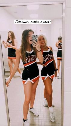 two women in cheerleader outfits are standing in front of a mirror