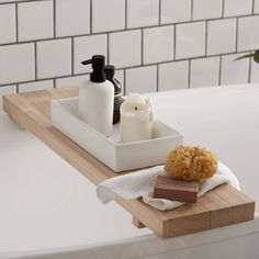 a bathtub with soap, sponges and other items on the tray in front of it