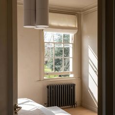 an empty bedroom with a radiator, window and light coming through the room