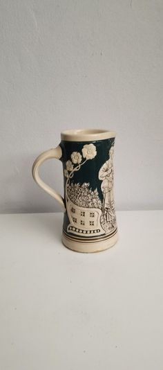 a black and white coffee mug sitting on top of a table next to a wall