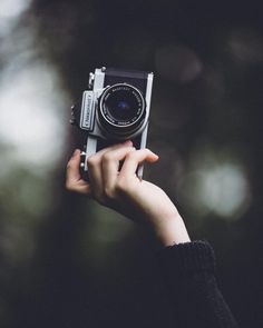 a person holding an old fashioned camera up to their face in front of the camera