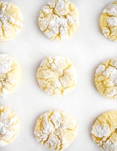 twelve cookies are covered in powdered sugar on a white surface with one cookie missing