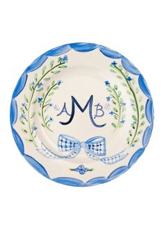 a blue and white plate with an initial monogrammed on the front, and a bow tie at the bottom