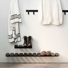 a pair of shoes sitting on top of a black shelf next to a coat rack