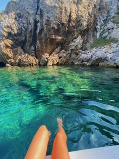 a person is sitting on a boat looking out at the water and cliffs in the background