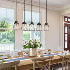 a dining room table and chairs with flowers in a vase on the centerpieces