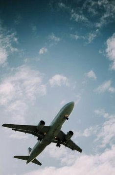 an airplane is flying in the sky on a clear day with some clouds behind it