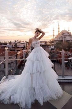 a woman standing on top of a building wearing a white dress