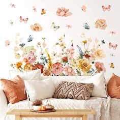 a white couch sitting next to a wall covered in lots of flowers and butterfly decals