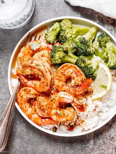 a bowl filled with shrimp, rice and broccoli next to a glass of water