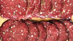 several slices of salami sitting on top of a cutting board