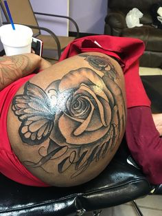 a man with a rose tattoo on his stomach sitting in a chair next to a cup