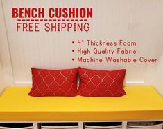 the bench cushion is free shipping and has four red pillows on it, along with three white drawers