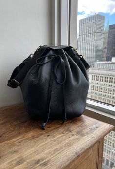 "For more handmade leather bags, purses, satchels, messengers, travel bags, holdalls, carry alls, handbags, shoulder bags, click here: http://etsy.me/1muiXbL. Large size bucket bag is made out of soft black bison leather and soft black leather strap. Its easily opens and closes with the leather drawstring, it expansionists and minimizes very easily and turns a purse into a weekender. Our bucket bag comes with an adjustable and removable leather strap, brass hardware and large hanging pocket. Mad Bison Leather, Soft Leather Handbags, Black Leather Crossbody Bag, Leather Notebook, Handbag Black, Black Leather Handbags, Leather Bucket Bag, Leather Bucket, Leather Bags Handmade