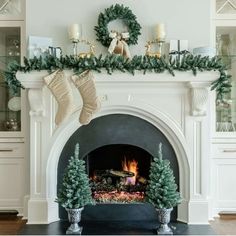 a decorated fireplace with stockings and christmas wreaths