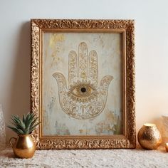 an ornate gold frame with a hamsa hand painted on it and a potted plant next to it