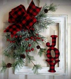 a red and black plaid christmas wreath with the word joy hanging on a white door