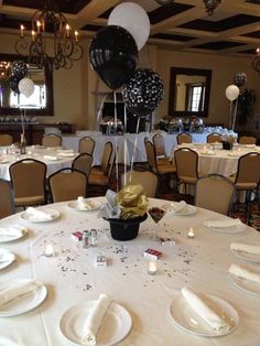 a table set up for a party with black and white balloons