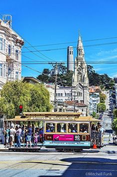 a trolley car is traveling down the street in san francisco, california on a sunny day