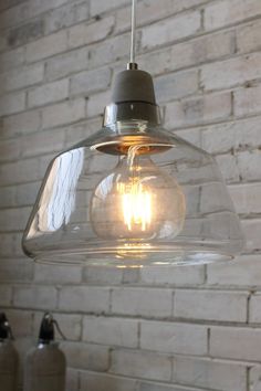 a light fixture hanging from a brick wall in a room with exposed lighting and white bricks