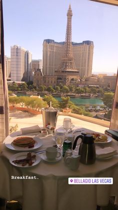 the table is set for breakfast in front of the view of the eiffel tower