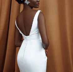 a woman in a white dress is standing with her back turned to the camera and wearing earrings