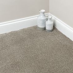 two white vases sitting on top of a carpeted floor