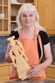 a woman in an orange apron is holding a wooden statue