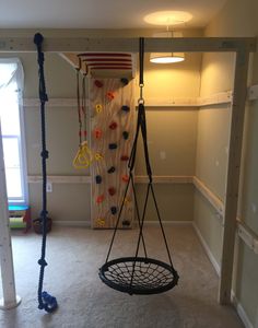 an empty room with a swing and climbing rope