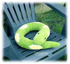 a green stuffed snake sitting on top of a wooden chair