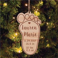 a personalized ornament hanging from a christmas tree with lights in the background