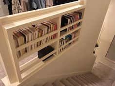 there is a book shelf with books on it and stairs leading up to the closet