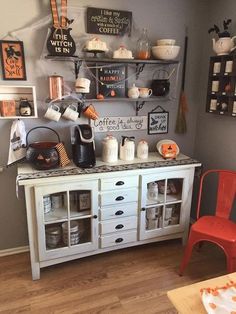 a kitchen with white cabinets and lots of halloween decorations on the wall above it, along with red chairs