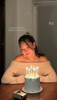 a woman sitting in front of a cake with candles on it