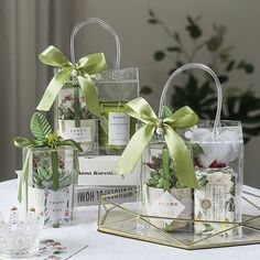 three clear gift bags with green bows on them sitting on a table next to other items