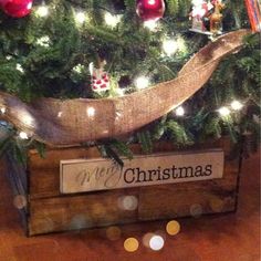 a christmas tree with ornaments and lights on it's branches in a wooden crate