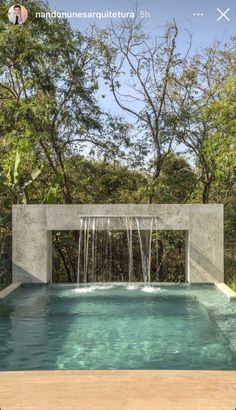 an outdoor swimming pool with waterfall in the middle and trees around it, surrounded by greenery