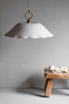 a wooden table topped with mushrooms under a white light hanging from a ceiling lamp over it