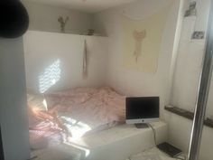 a bed room with a computer on top of it and a window in the corner