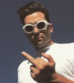 a man in white shirt and sunglasses pointing at something