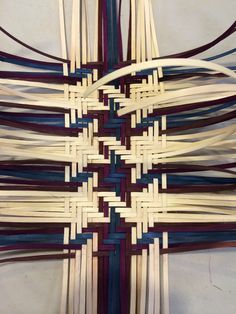 a cross made out of strips of wood and woven with blue, white, and red stripes