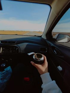 a person driving a car on the road with their hand on the steering wheel and looking out the window