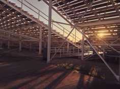 the sun shines through some metal structures in an open area with grass and dirt