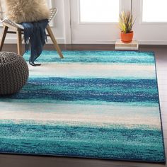 a blue and white rug in a living room with a chair, potted plant and window