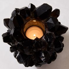 a candle that is sitting in some kind of black object on a table next to a white wall