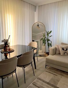 a living room filled with furniture next to a window covered in white drapes and curtains