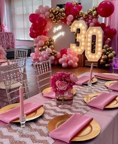 a table set up for a 30th birthday party with pink and gold plates, napkins, candles and balloons