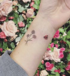 a ladybug tattoo on the wrist with pink flowers behind it and a ladybug