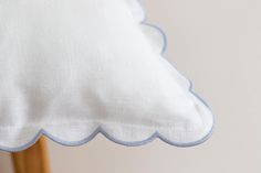 a white pillow with blue trim on top of a wooden chair next to a wall